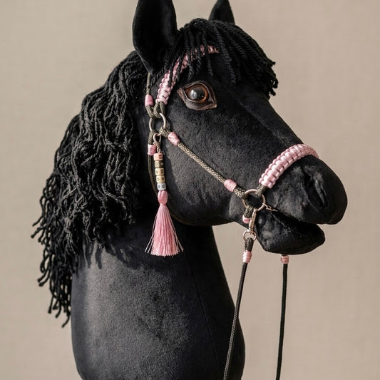 Black handmade hobby horse with pink bridle, reins, and personalized tassel name tag – custom hobby horse toy on studio background.