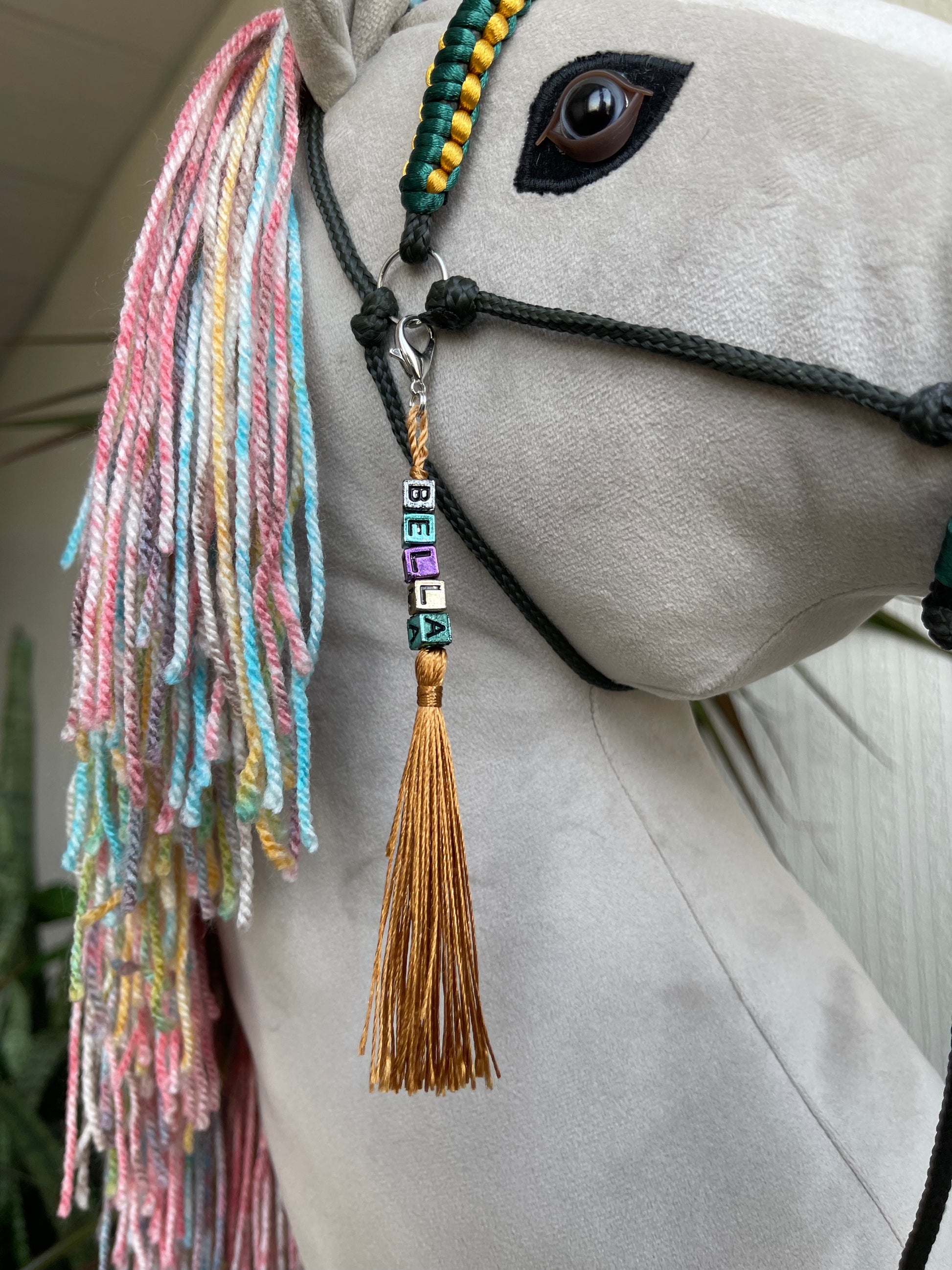 Light gray hobby horse with rainbow mane and green bridle, handmade stick horse for children role play and hobby horse riding.