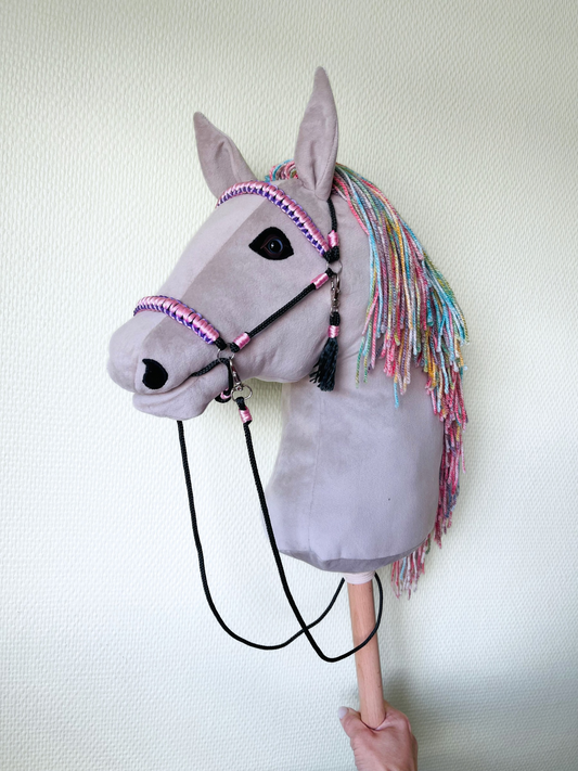 Light gray handmade hobby horse with rainbow mane and pink bridle, stick horse toy for kids and hobby horsing.