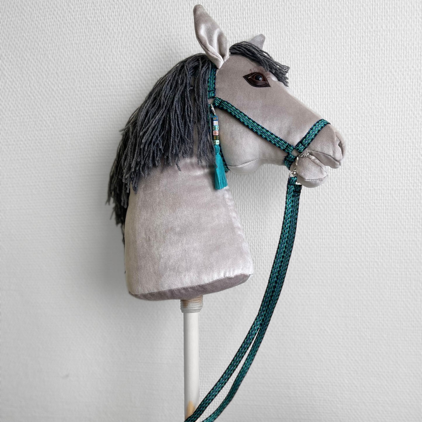Handmade gray hobby horse, side view on neutral studio background