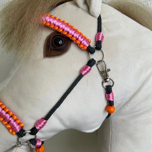 Close-up of handmade hobby horse wearing pink and orange bridle with reins and personalized tassel name tag