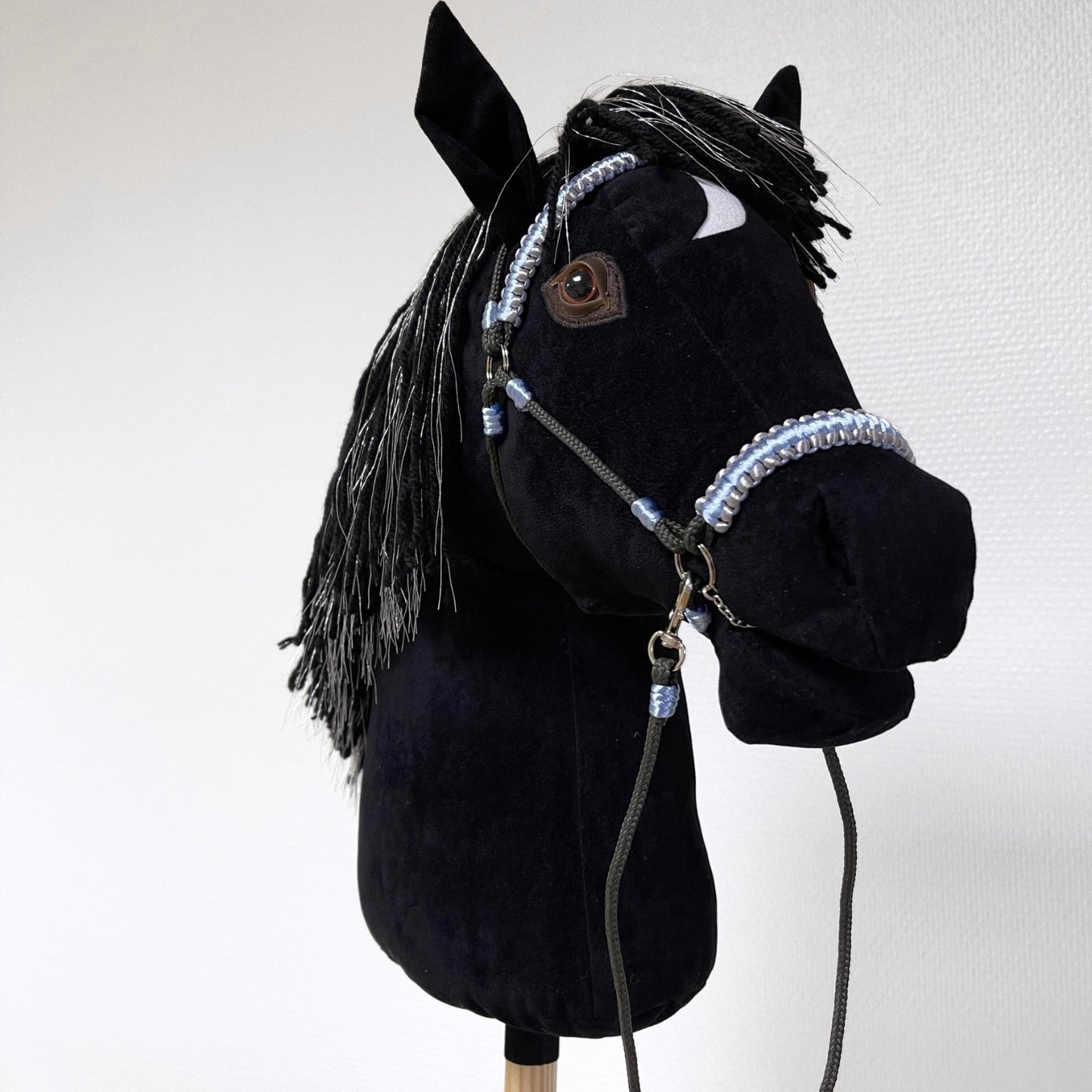 Black hobby horse with silver-threaded mane and light blue bridle, handmade stick horse with personalized pendant.