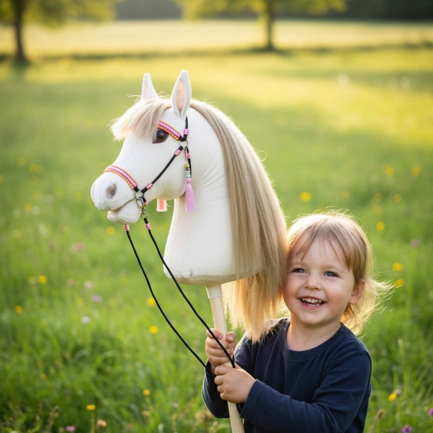 Child holding a handmade beige hobby horse with faux hair mane outdoors, hobby horsing toy for kids.