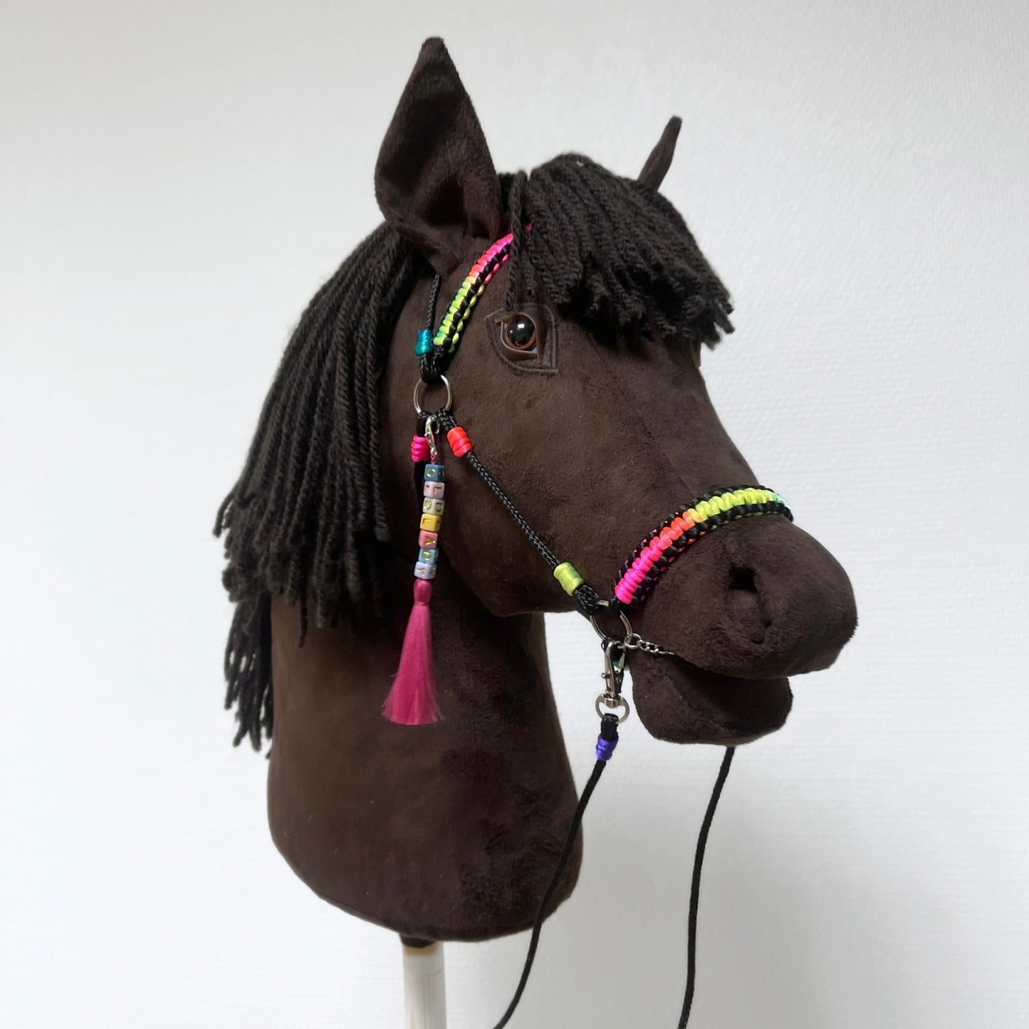 Dark brown hobby horse side profile with rainbow reins and yarn mane – handmade stick horse