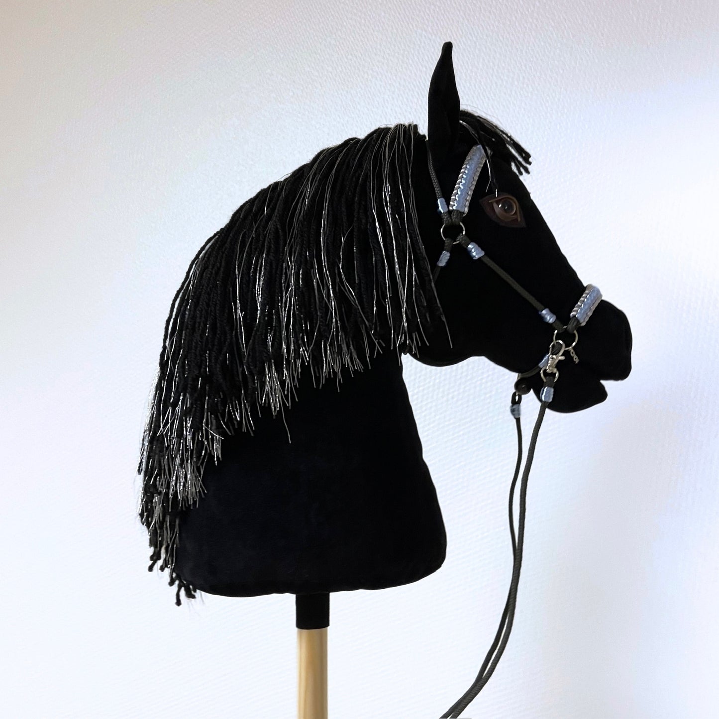 Black hobby horse with silver-threaded mane and light blue bridle, handmade stick horse with personalized pendant.