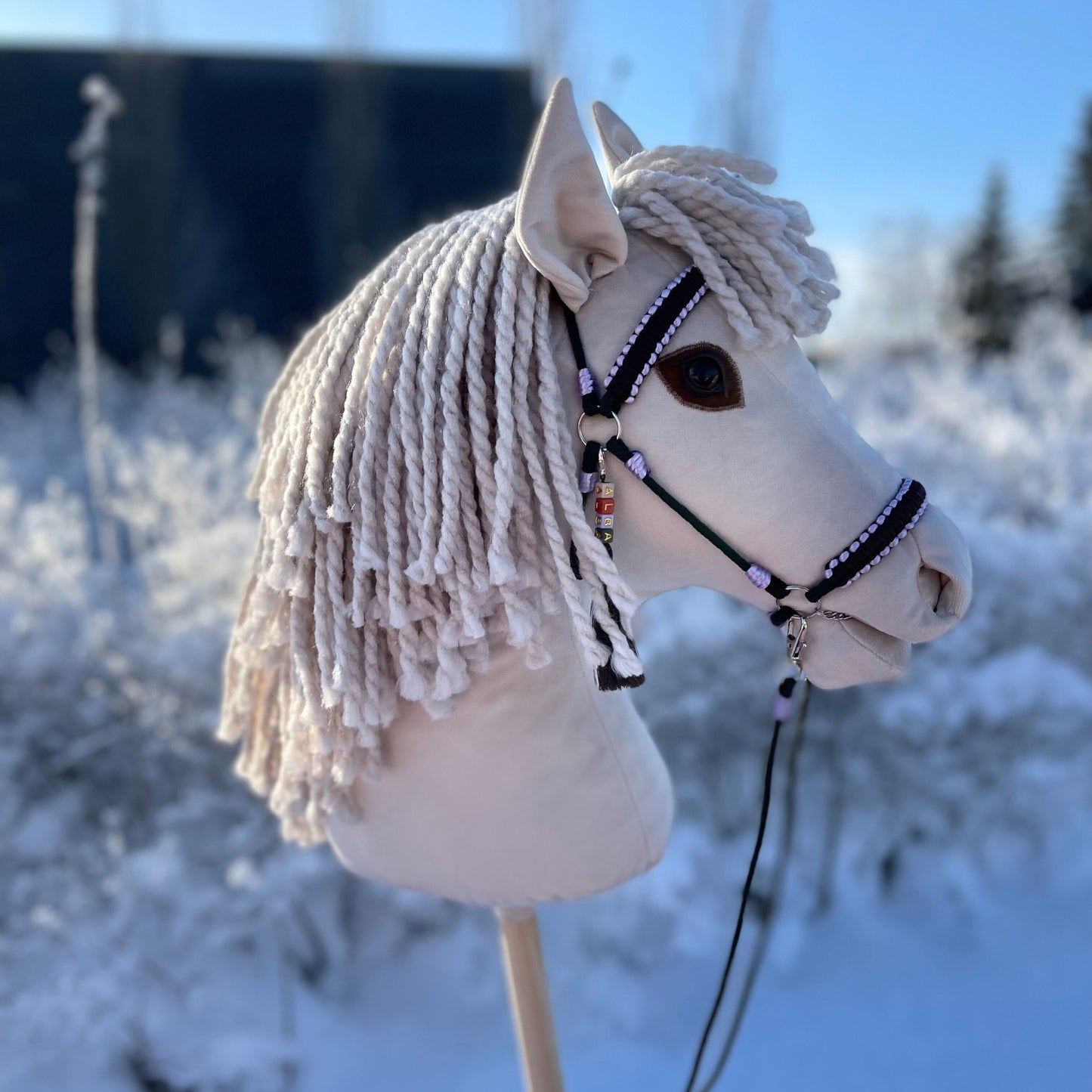 Ivory beige handmade hobby horse with yarn mane, photographed outdoors in winter nature