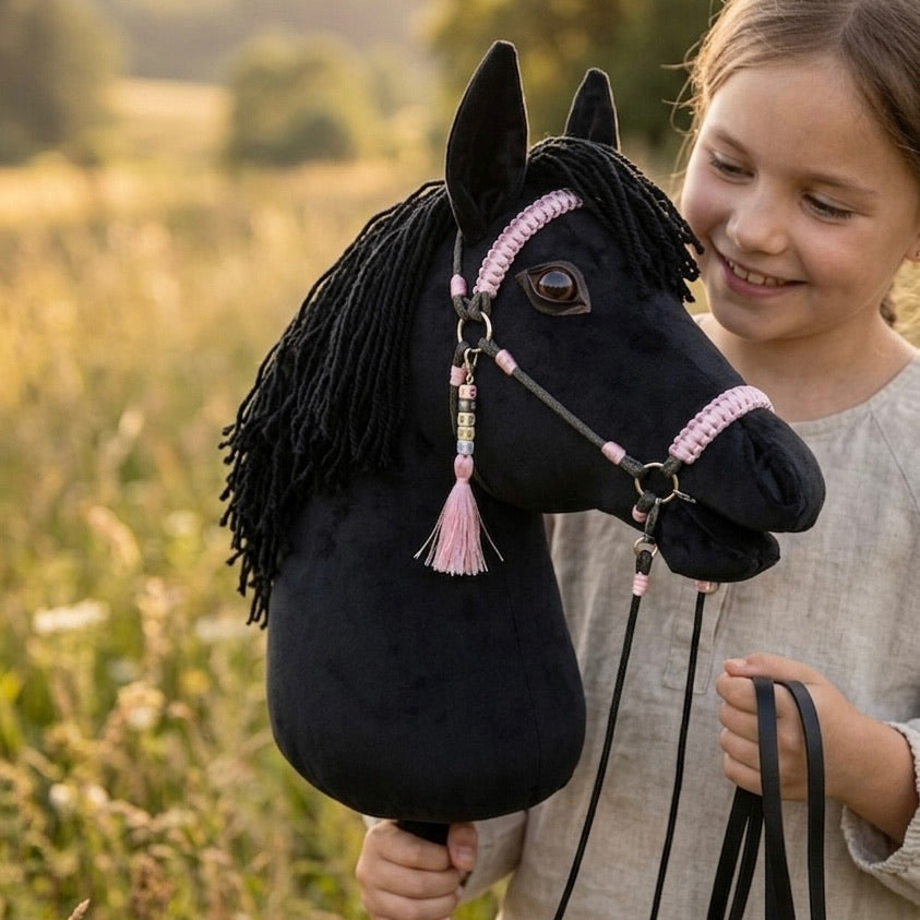 Girl holding a black handmade hobby horse with pink accessories – personalized hobby horse toy for kids.