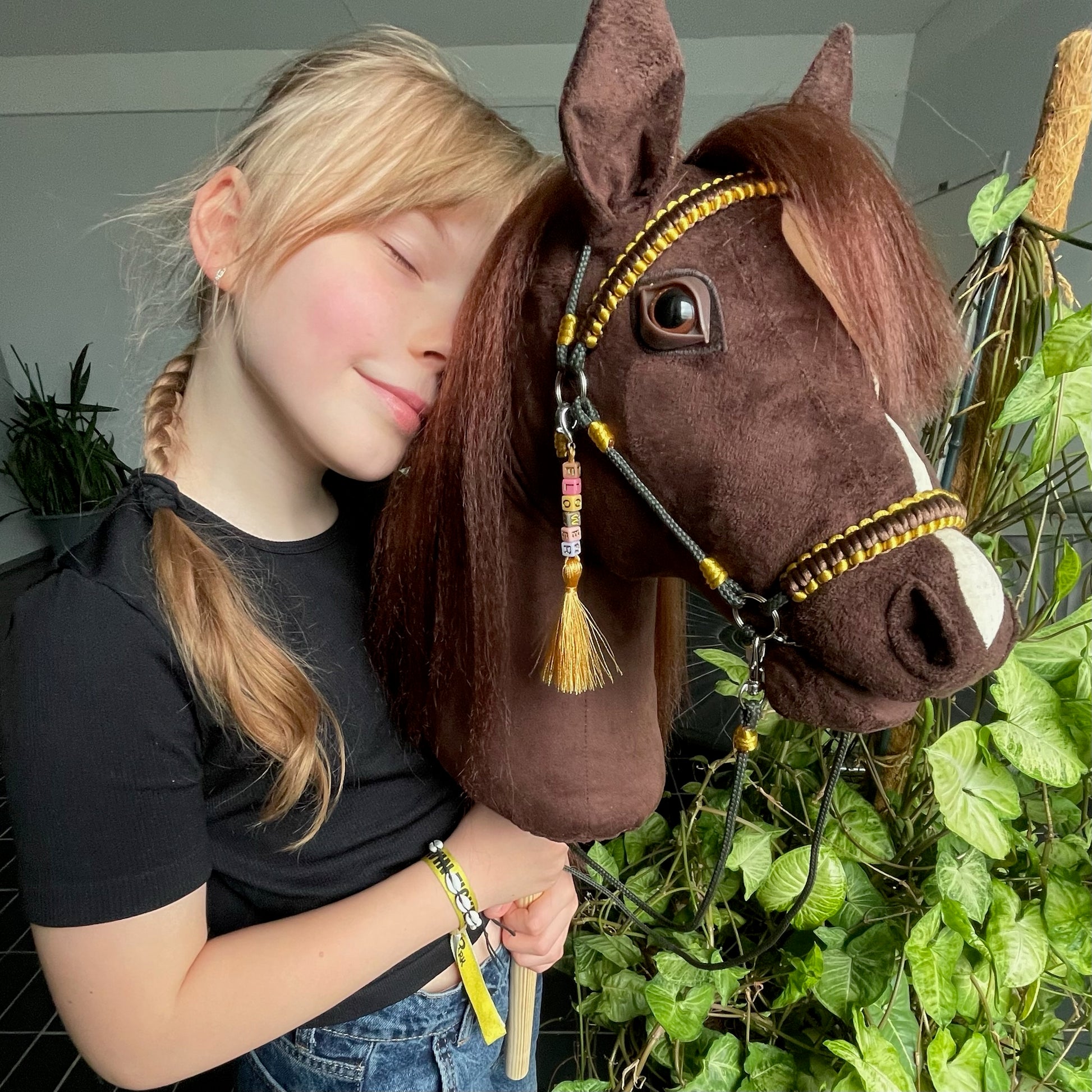 Smiling girl holding a handmade dark brown hobby horse, realistic stick horse toy and personalized gift for kids, capturing a joyful outdoor moment with a premium handcrafted hobby horse