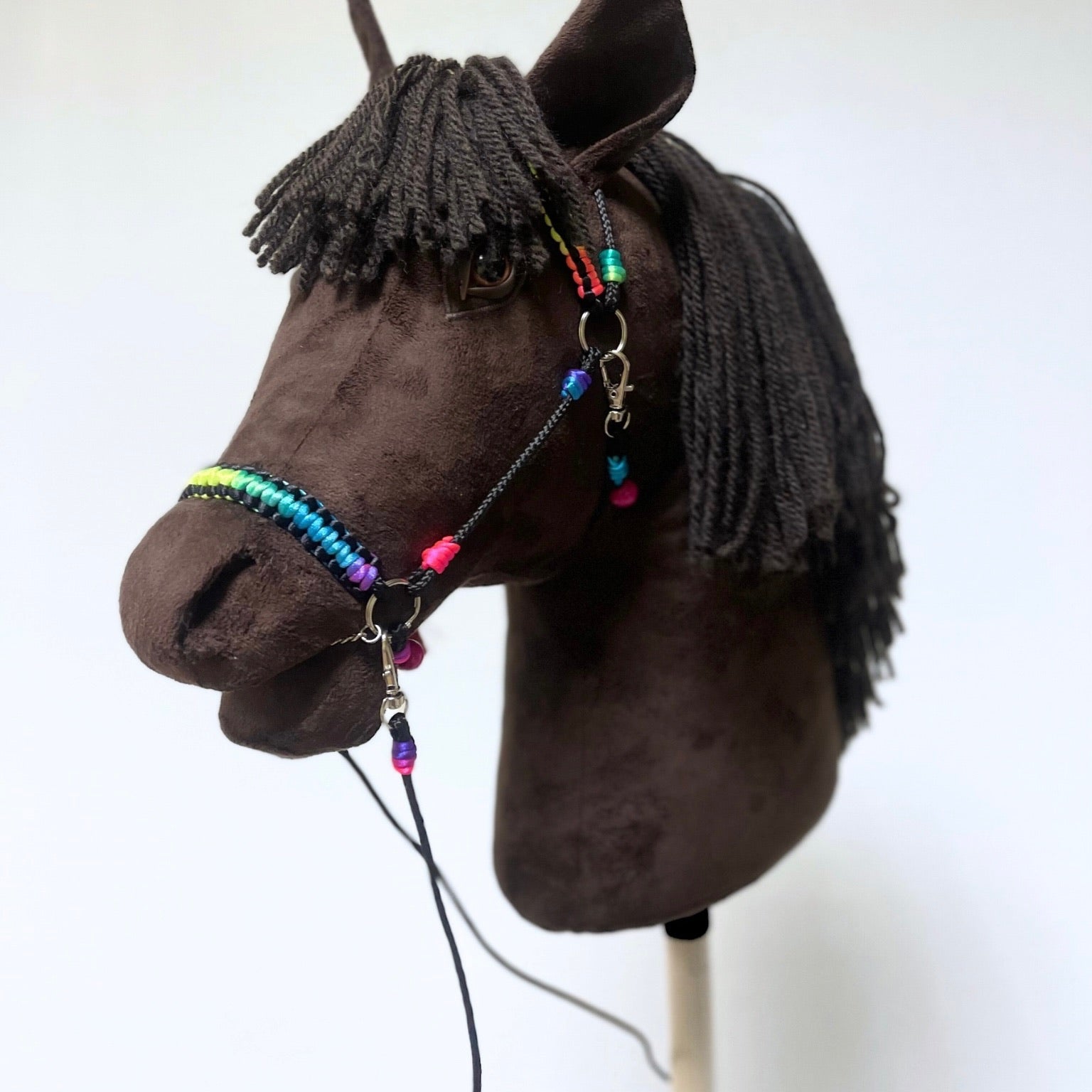Side view of dark brown handmade hobby horse with yarn mane and colorful bridle – stick horse toy