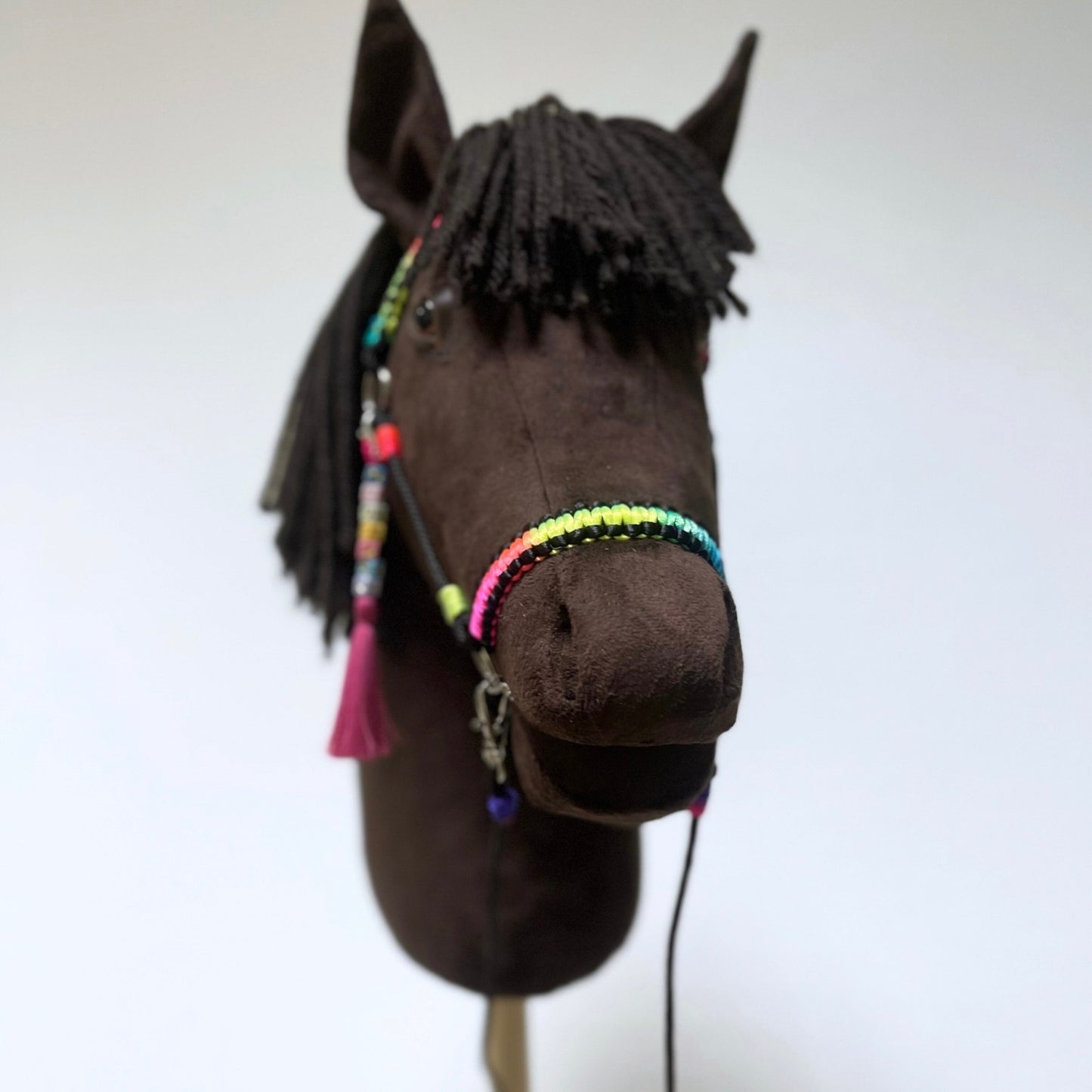 Front view of dark brown hobby horse with colorful bridle and yarn mane – handmade stick horse for kids