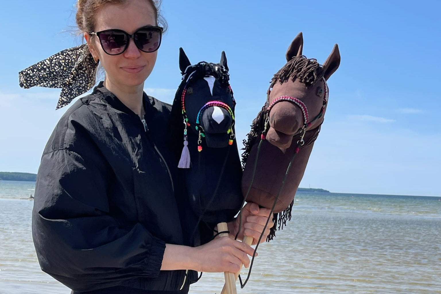 Artist holding two handmade hobby horses – creator of unique handcrafted hobby horse toys.
