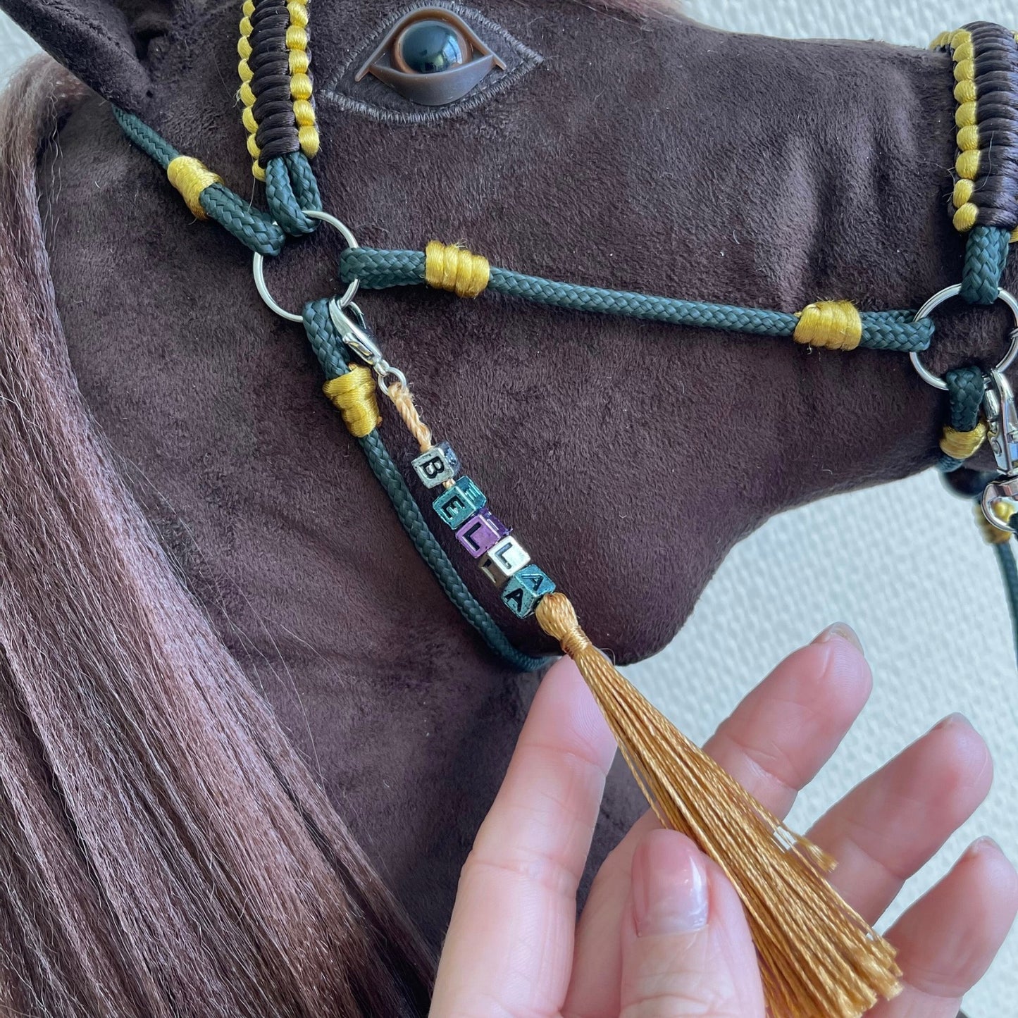 Close up of Bella hobby horse personalized tassel with golden letter beads on bridle