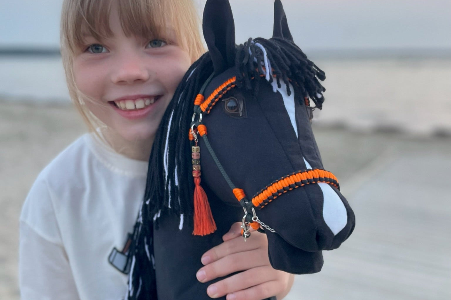 Smiling girl holding a handmade  hobby horse toy – unique handcrafted kids gift.