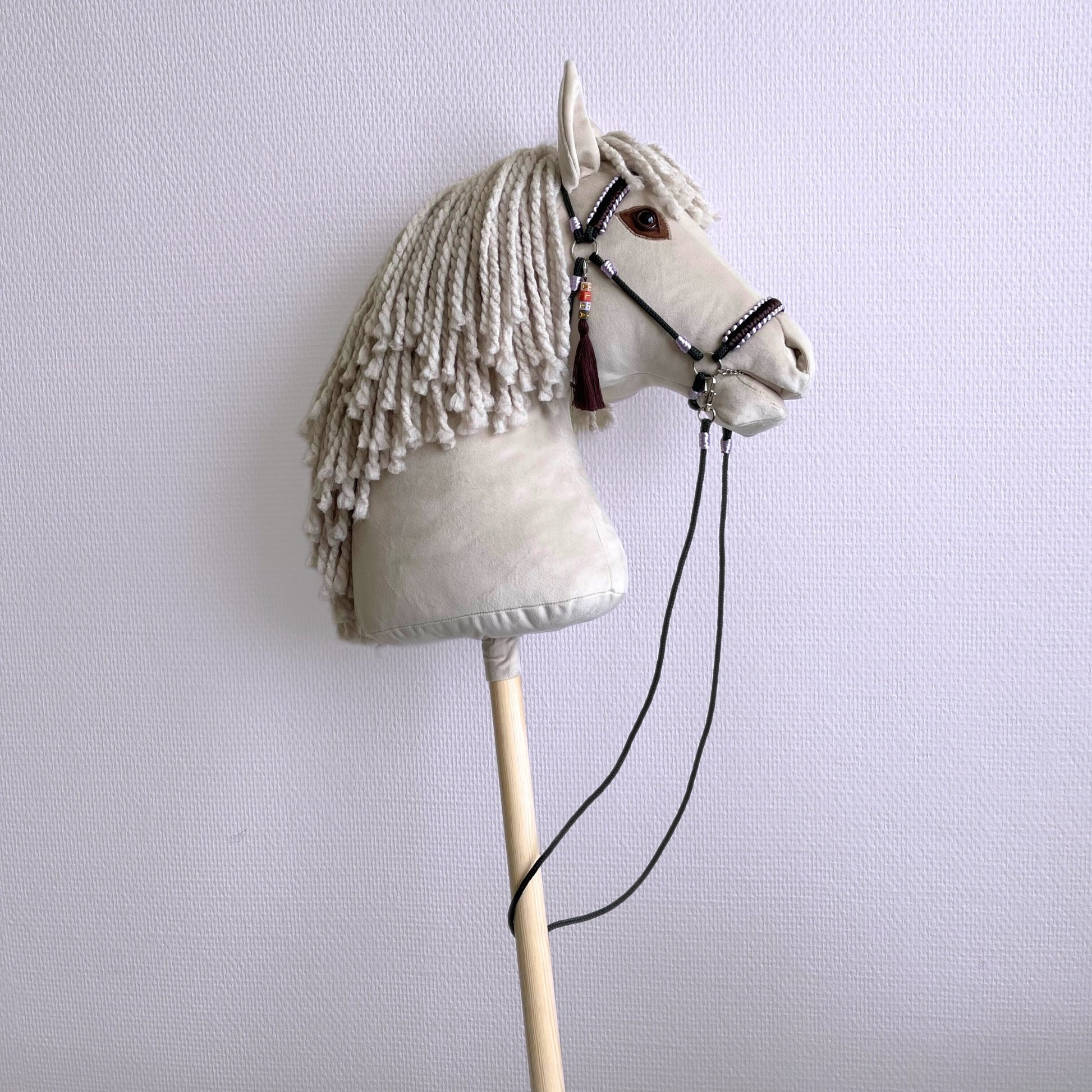 Side view close-up of ivory hobby horse head with hand-braided halter
