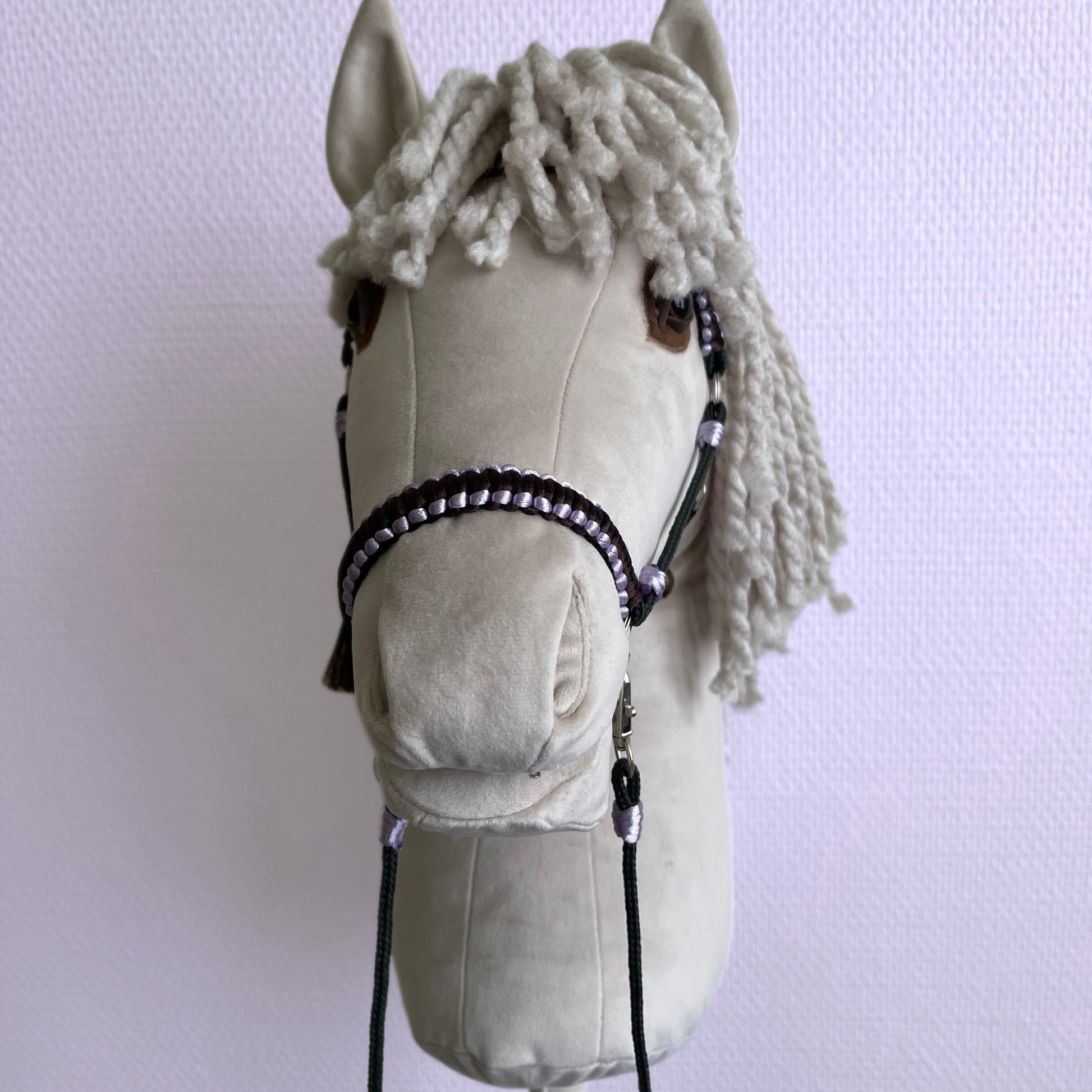 Front view close-up of handmade ivory hobby horse with yarn mane