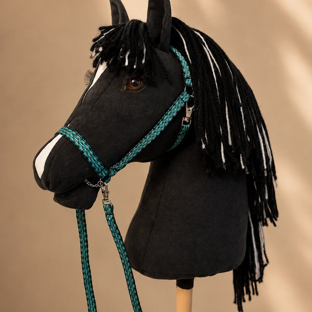 Side profile of handmade black stick horse with yarn mane and turquoise reins