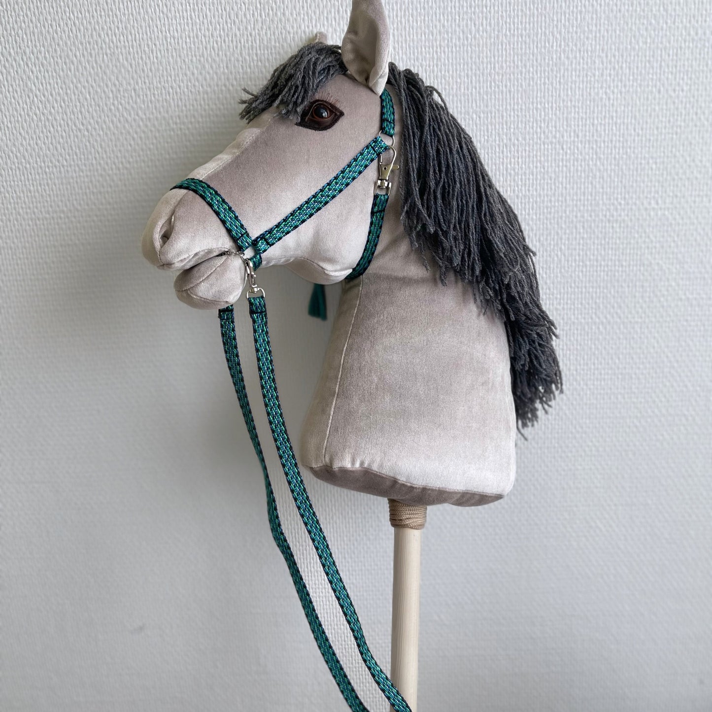 Handcrafted stick horse with yarn mane, profile view indoors