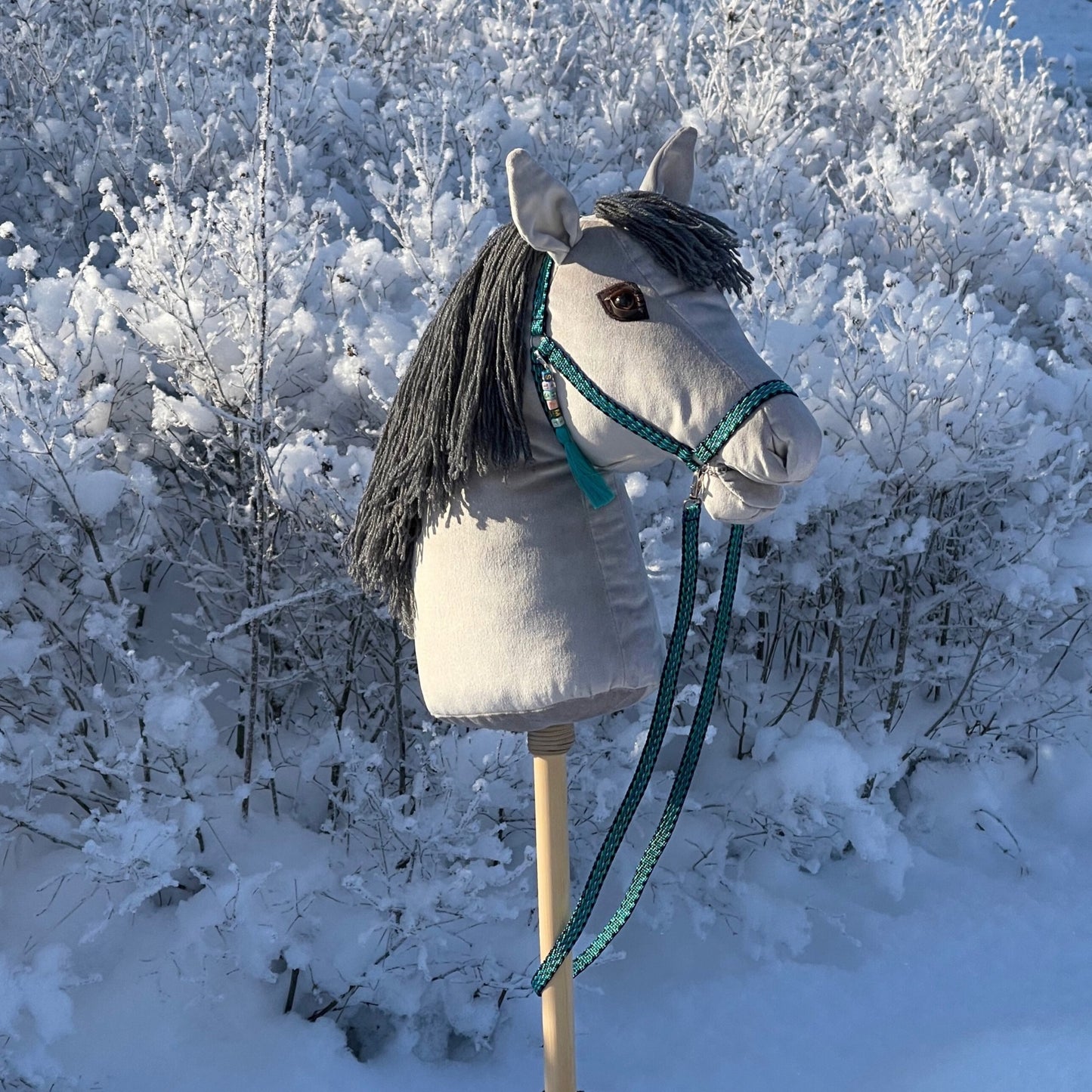 Handcrafted hobby horse in winter scenery, yarn mane and bridle details